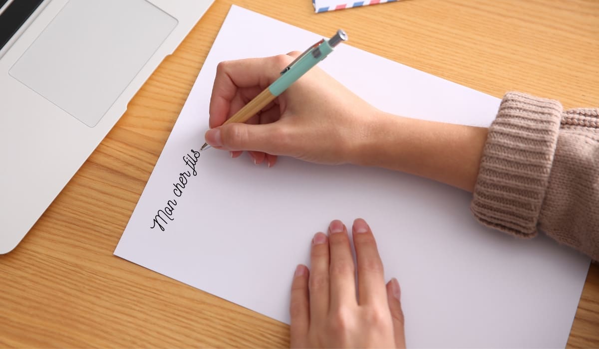 Une femme écrit une lettre à son fils adulte.