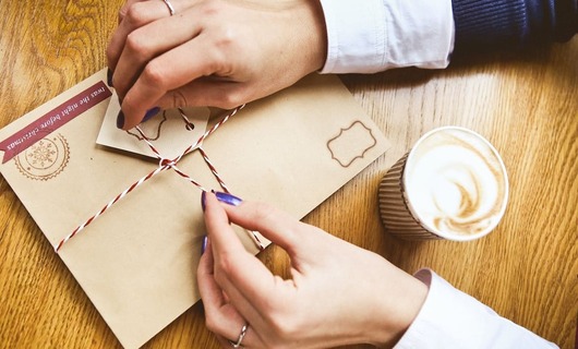 Une femme ouvre sa lettre recommandée à côté de son café