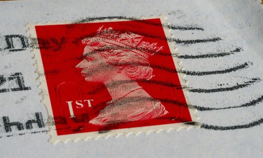 Image d’un timbre rouge symbolisant affranchissement lettre suivie.