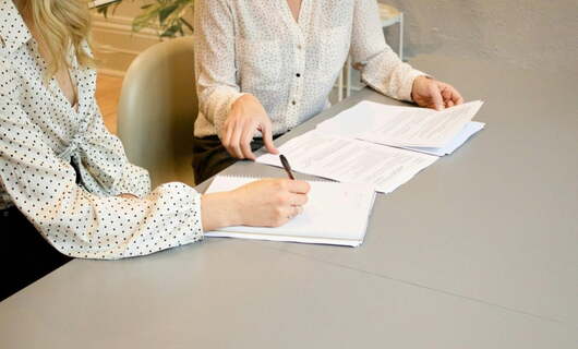 Deux femmes assises discutent de la lettre de licenciement d’un salarié avant de l’envoyer avec une lettre recommandée avec accusé de réception.