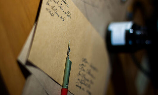 Une enveloppe marron prête à être affranchie, se trouvant sur une table, contient une lettre sur laquelle l'expéditeur a posé son stylo.