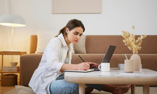 Une lycéenne assise auprès de son laptop rédige sa lettre de motivation qu'elle enverra après son inscription sur Parcoursup.