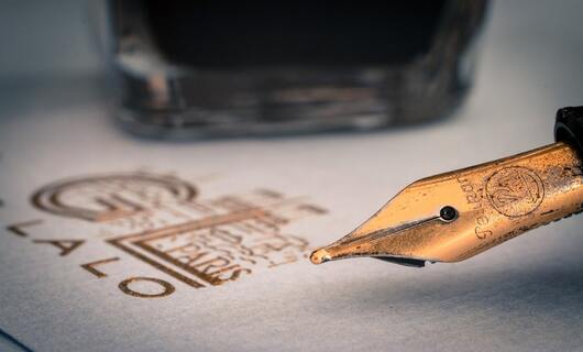 Une personne écrit sa lettre d’excuses professionnelles avec son stylo-plume.
