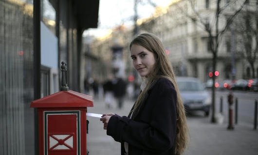 Une jeune femme s'apprête à envoyer son courrier express en utilisant une boîte aux lettres.