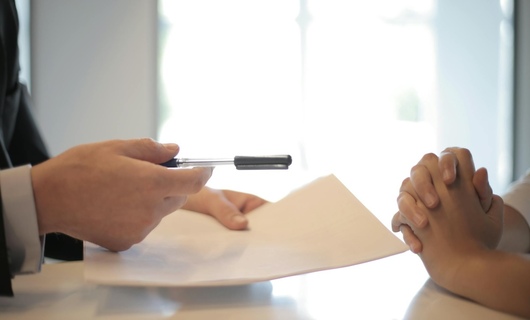 Une femme s’apprête à signer la lettre pour résilier une assurance voiture.
