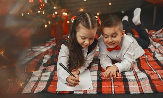 Deux enfants écrivent un courrier au Père Noël.