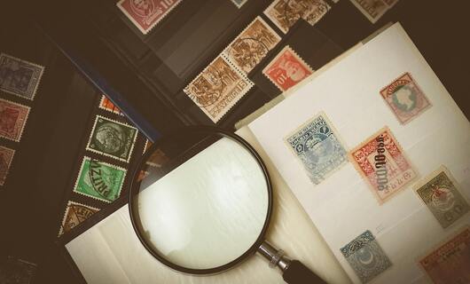 Un stock d'ancien timbre gris, rouge et vert est placé sur des enveloppes.