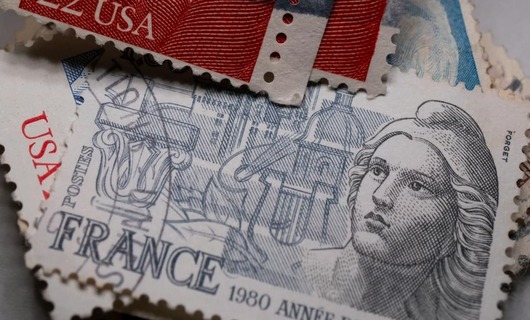 Un homme adresse une enveloppe avant d'envoyer une lettre à l'étranger avec un timbre français.