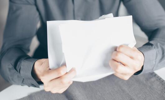 Un homme froisse sa lettre à un voisin bruyant avec colère.