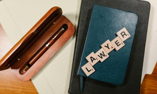 Un carnet et un stylo sont utilisés pour préparer la rédaction d'une lettre à un avocat.