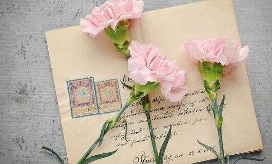 Une femme prépare des roses et une enveloppe pour envoyer une lettre à sa meilleure amie.