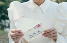 Une femme tient une enveloppe timbrée dans ses mains et s'apprête à lire la lettre qu'elle s'est envoyée lorsqu'elle était une jeune fille.
