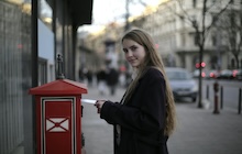 Une jeune femme s'apprête à envoyer son courrier express en utilisant une boîte aux lettres.