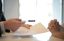 Une femme s’apprête à signer la lettre pour résilier une assurance voiture.