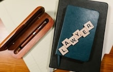 Un carnet et un stylo sont utilisés pour préparer la rédaction d'une lettre à un avocat.